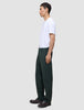 Eine Person im Profil trägt ein weißes T-Shirt, eine dunkelgrüne Ease-Hose Relaxed Fit Northern Pine und dunkelbraune Slipper.