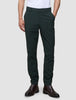 Eine Person, die eine dunkelgrüne Ease Pants Slim Northern Pine und braune Lederstiefel trägt.
