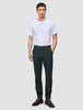 Eine Person, die ein weißes T-Shirt, eine Ease Pants Slim Northern Pine in Dunkelgrün und braune Lederschuhe trägt.