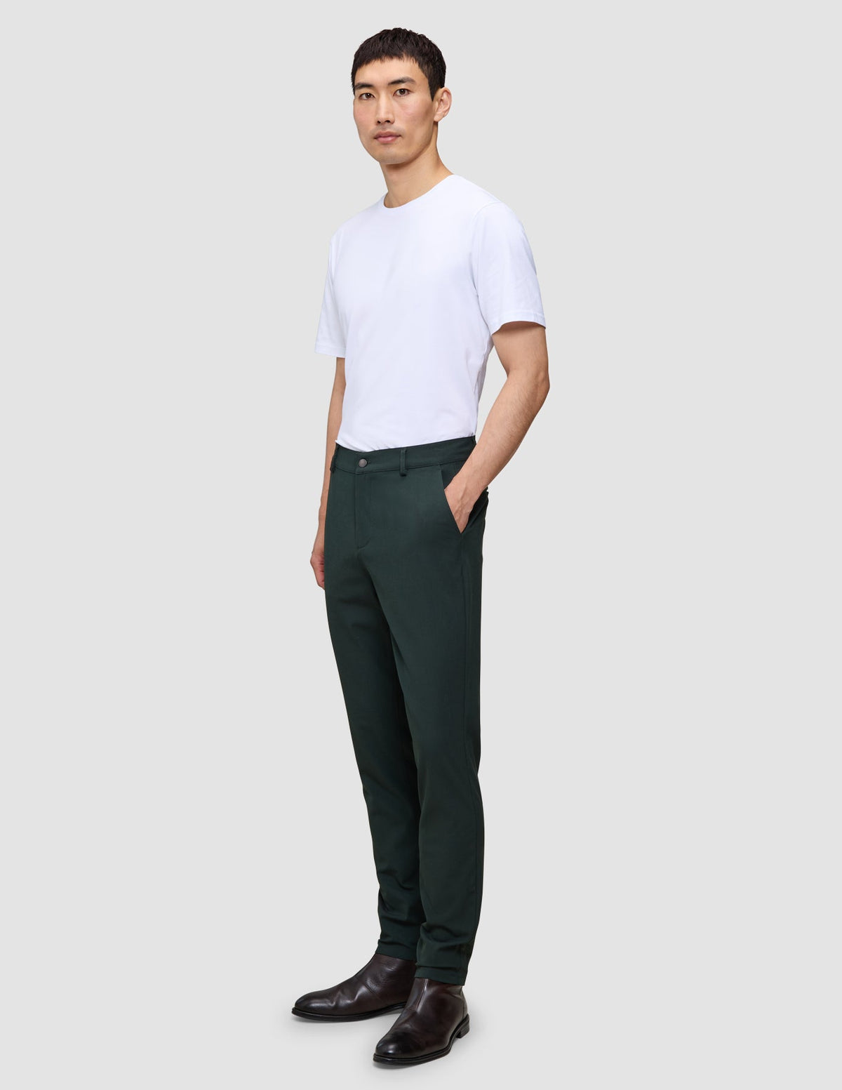 Ein Mann, der ein weißes T-Shirt, eine Ease Pants Slim Northern Pine und dunkle Lederschuhe trägt.