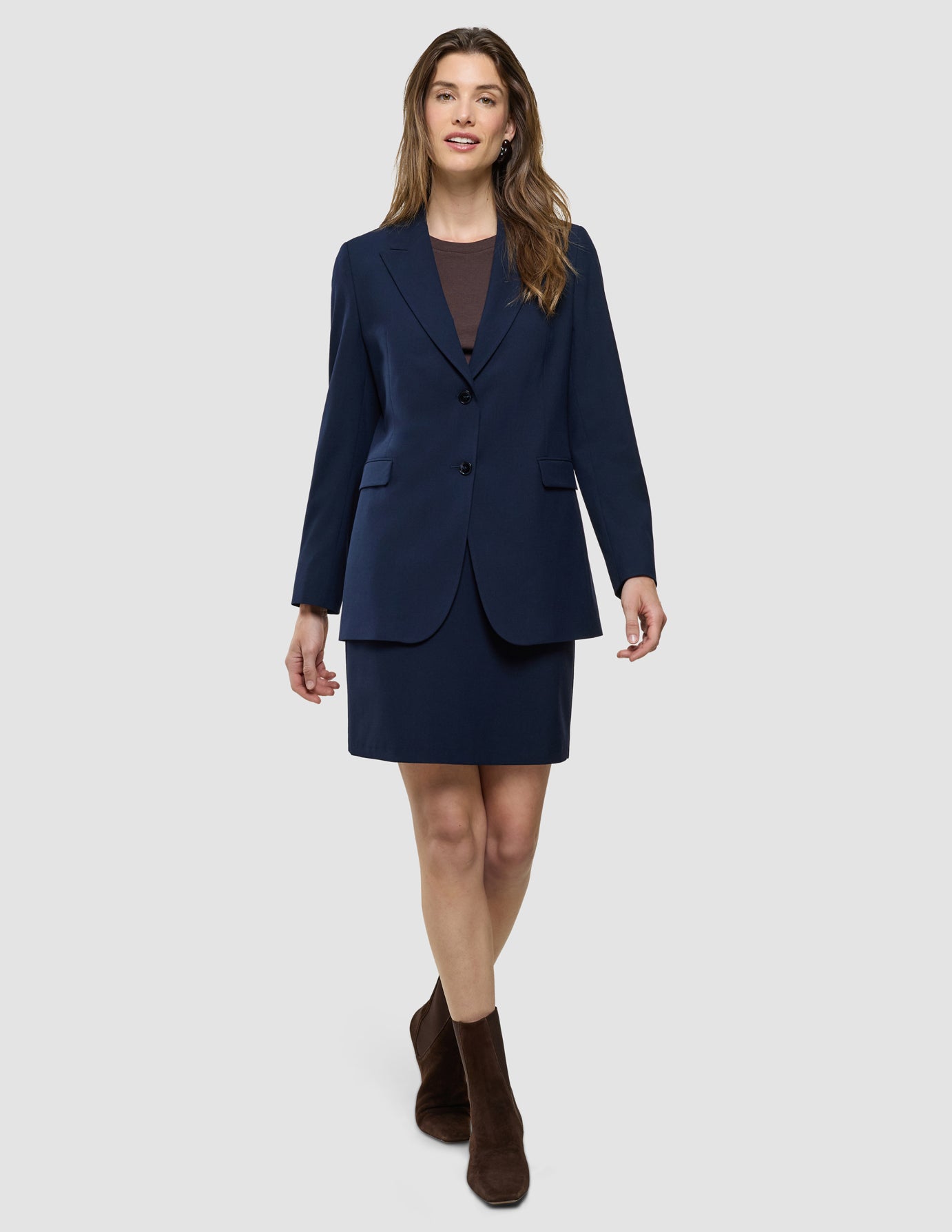 Eine Frau, die einen marineblauen Blazer und den „Women Ease Short Skirt Blue Nights“ über einem dunkelbraunen Oberteil trägt, dessen Stil vom skandinavischen Design inspiriert ist.