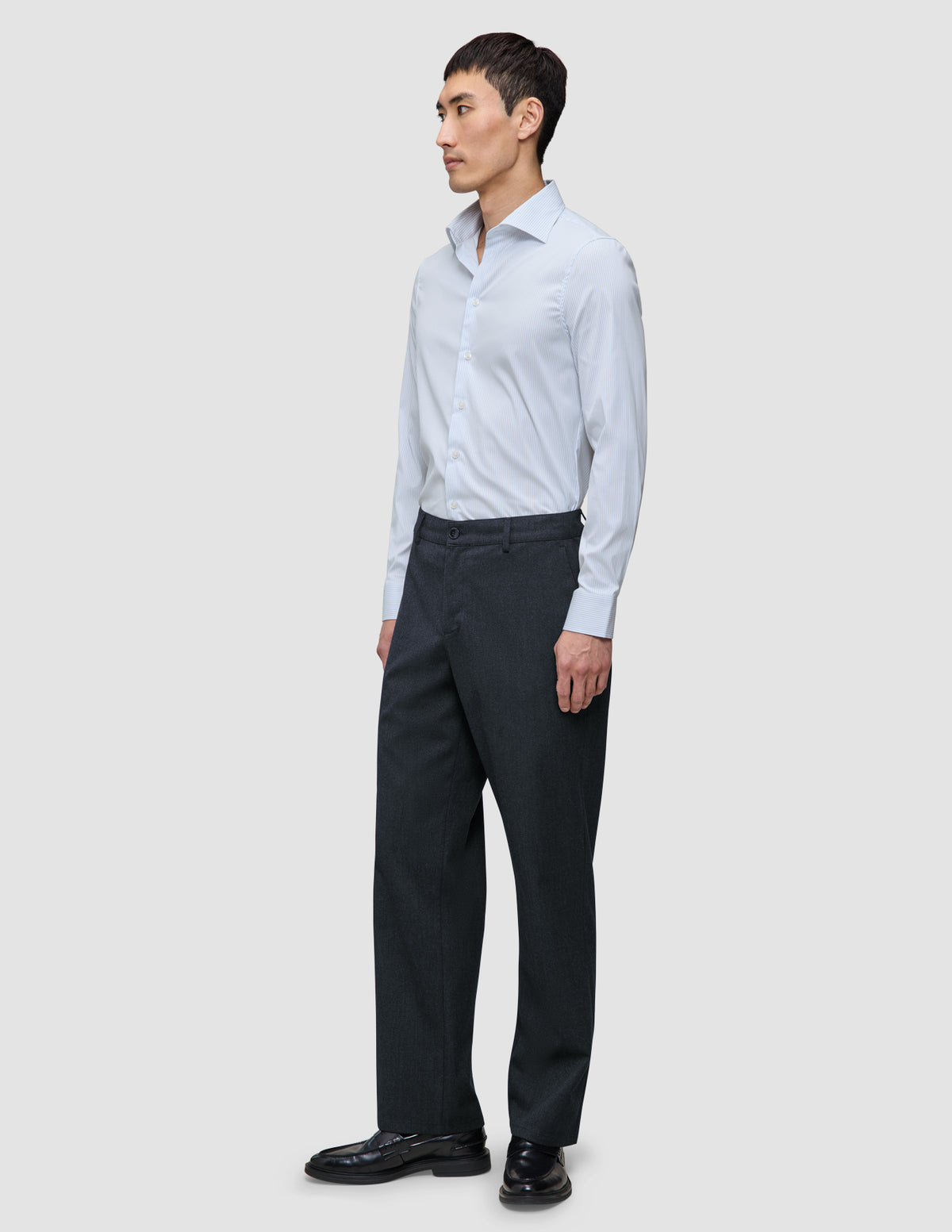 Ein Mann, der ein Elevated Shirt Regular Classic Blue Striped mit hellblauen Streifen, eine dunkle Hose und schwarze Anzugschuhe trägt.