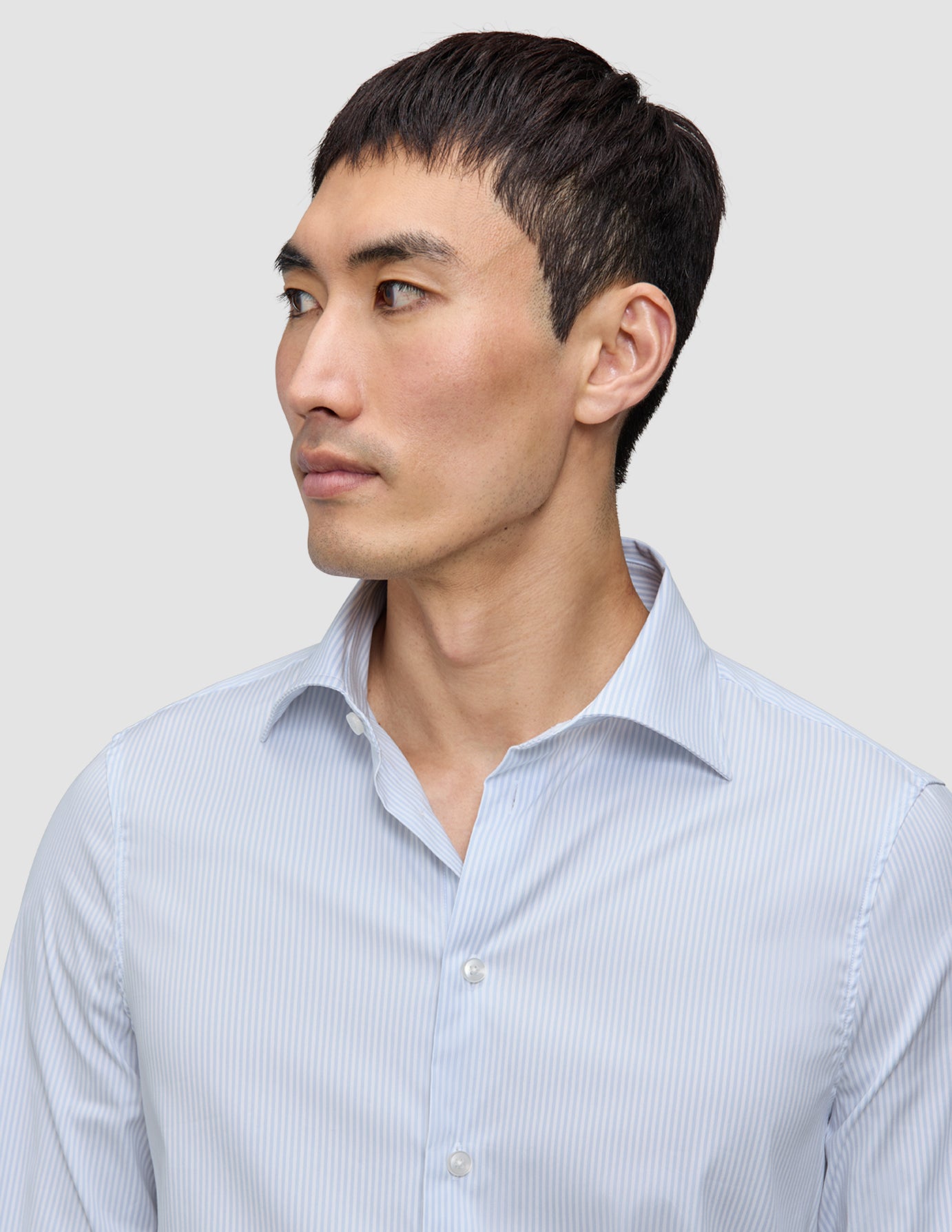 Ein Mann, der ein Elevated Shirt Regular Classic Blue Striped aus hellblau-weiß gestreifter Pima-Baumwolle trägt.