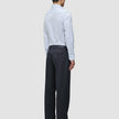 Eine Person, von hinten gesehen, die ein hellblaues, feinn gestreiftes Elevated Shirt Slim Classic Blue Striped-Hemd mit Knopfleiste trägt, das in eine dunkelgraue Hose gesteckt ist, sowie schwarze Loafer.