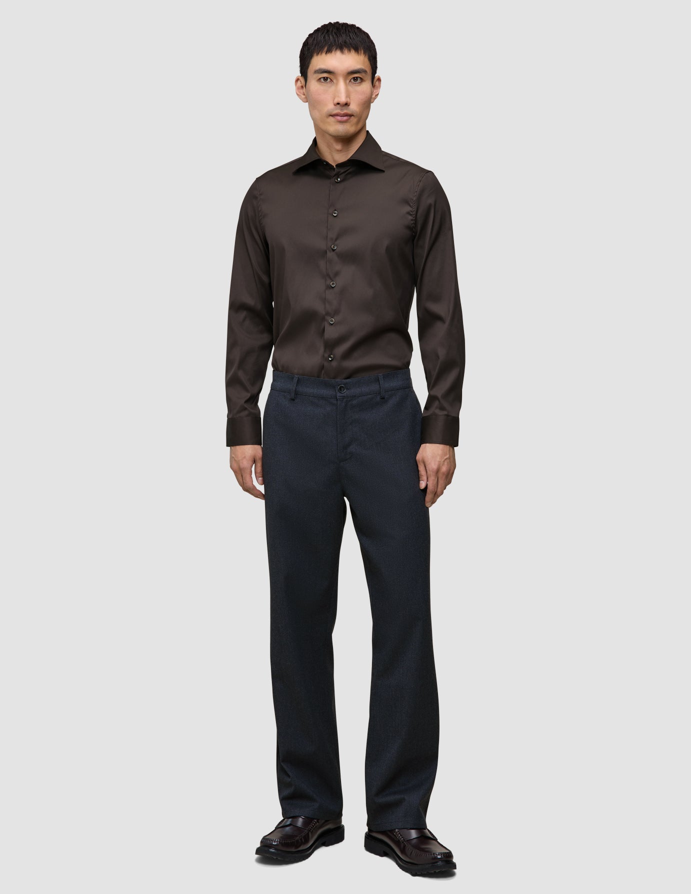 Ein Mann, der ein dunkelbraunes Elevated Shirt Slim, eine dunkle Hose und dunkle Lederschuhe trägt.