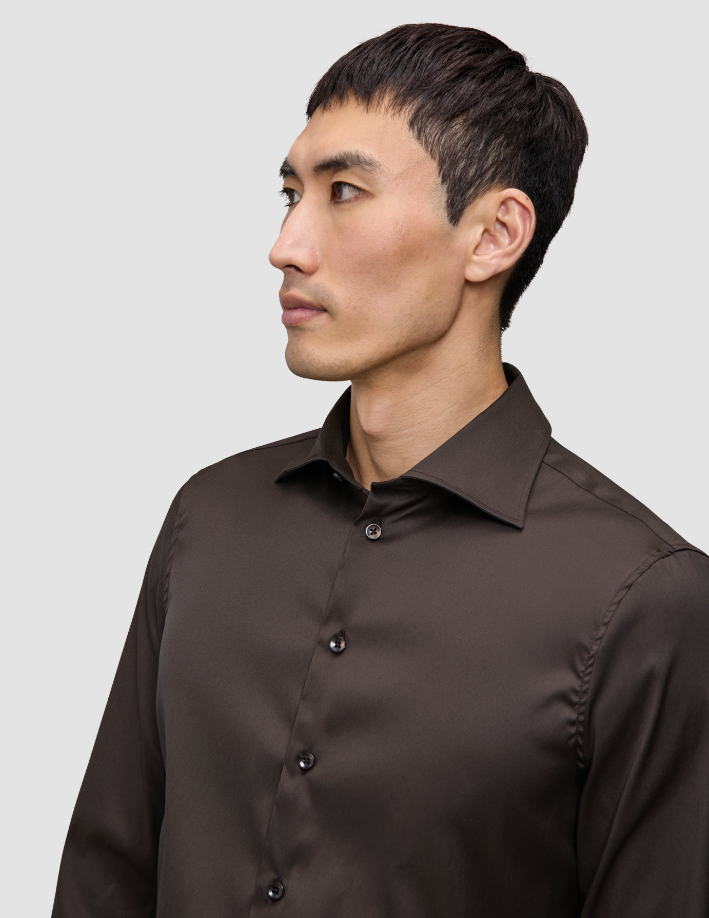 Ein Mann, der ein Elevated Shirt Slim Dark Brown trägt, ein dunkelbraunes, schmal geschnittenes Hemd mit Knöpfen.