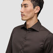 Ein Mann, der ein Elevated Shirt Slim Dark Brown trägt, ein dunkelbraunes, schmal geschnittenes Hemd mit Knöpfen.