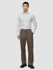 Ein Mann, der ein weißes, schmal geschnittenes Elevated-Hemd trägt, dazu eine braune Hose und dunkle Slipper.