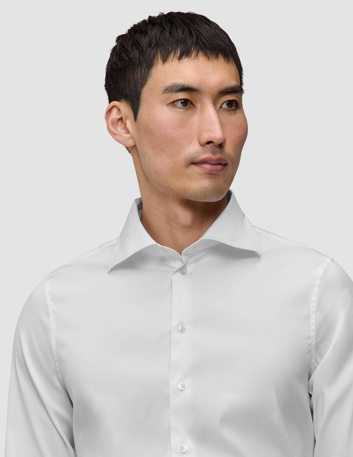 Eine Person, die ein Elevated Shirt White Slim trägt, ein knackig sitzendes, schmal geschnittenes weißes Hemd aus Pima-Baumwolle mit einem Spread-Kragen.