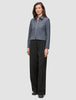 Eine Frau trägt eine Essential Short Zip Jacket in Dunkelgrau-Melange und eine schwarze Hose mit weitem Bein.