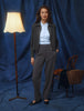 Eine Frau, die eine Essential Short Zip Jacket in Dunkelgrau-Melange über einem hellblauen Hemd und einer dunkelgrauen Hose trägt, was ein minimalistisches skandinavisches Design widerspiegelt.