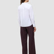 Eine Person, von hinten gesehen, die ein weißes Madison-Hemd und eine dunkle Nadelstreifenhose im klassischen, minimalistischen Stil trägt.