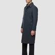Ein Mann, der einen dunkelgrauen Maxi-Wollmantel im minimalistischen skandinavischen Stil über einem Hemd und einer dunklen Hose trägt.
