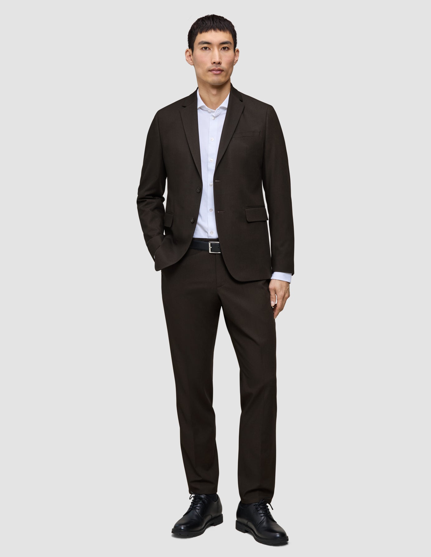 Ein Mann, der einen dunkelbraunen Motion Blazer Regular Cognac über einem weißen Hemd mit Kragen und dazu schwarze Schuhe trägt.