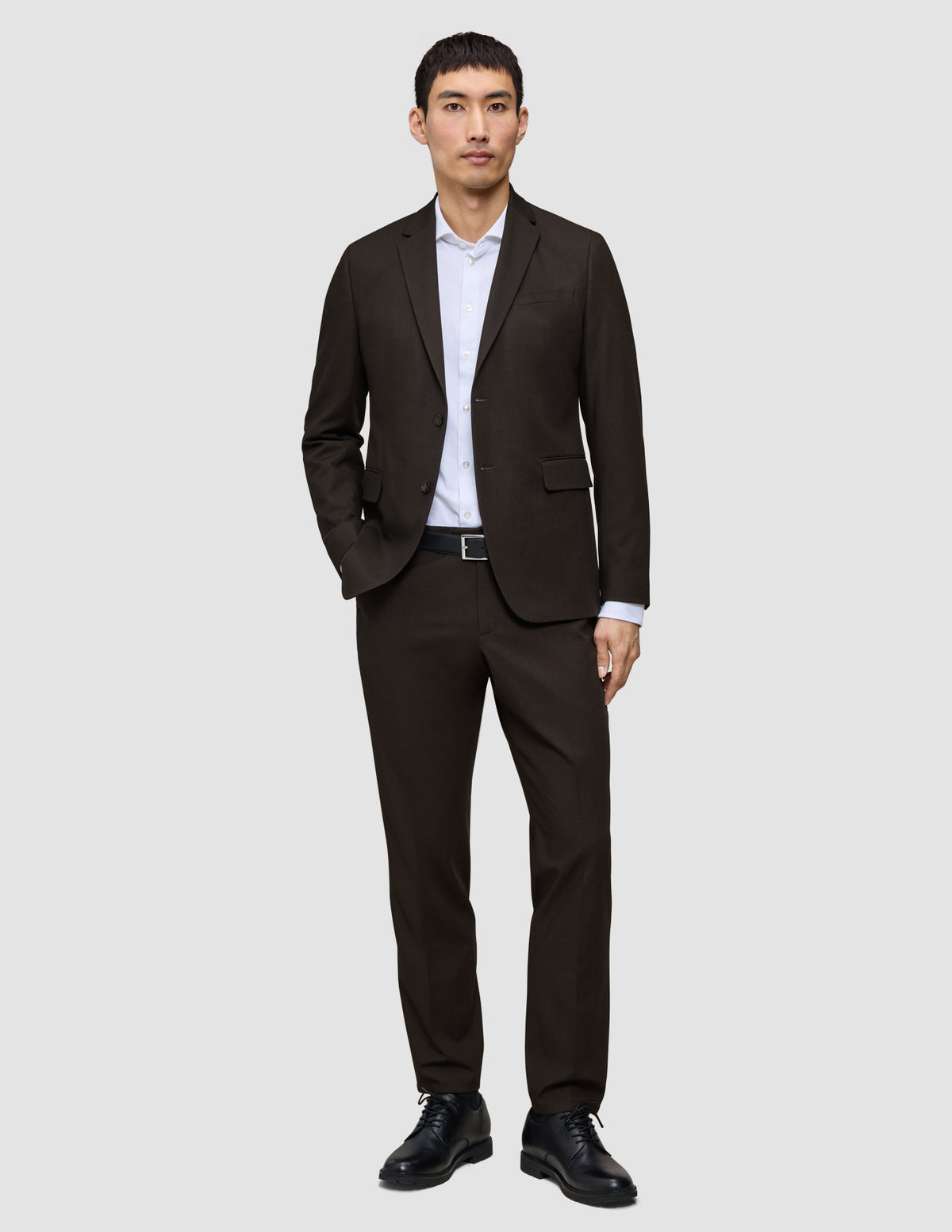 Ein Mann, der einen dunkelbraunen Motion Blazer Regular Cognac über einem weißen Hemd mit Kragen und dazu schwarze Schuhe trägt.