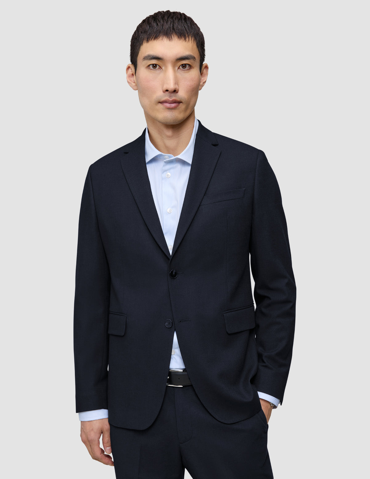 Ein Mann, der einen Motion Blazer Regular in Mitternachtsblau mit 360°-Stretch über einem hellblauen, Nadelstreifen-Hemd mit Knöpfen trägt.