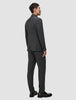 Eine Person im Profil trägt einen anthrazitfarbenen Motion Blazer Regular Pepper Grey mit 360°-Stretch und dunkle Slipper, die ein elegantes, skandinavisches Design präsentieren.