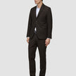 Ein Mann, der einen dunkelbraunen Motion Blazer Slim Cognac, ein weißes Hemd und schwarze Anzugschuhe trägt.