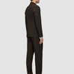 Ein Mann, der einen dunkelbraunen Motion Blazer Slim Cognac und ein weißes Hemd trägt, von der Seite gesehen, mit dunklen Anzugschuhen.