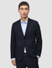 Ein Mann, der den Motion Blazer Slim Midnight Blue in Dunkelblau über einem hellblauen Nadelstreifenhemd trägt und damit das klare skandinavische Design zur Geltung bringt.