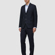 Ein Mann, der einen Motion Blazer Slim in Mitternachtsblau aus 360°-Stretch-Material, ein hellblaues Hemd mit Knöpfen und dunkle Slipper trägt.