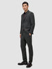 Ein Mann, der einen Motion Blazer Slim in der Farbe Pepper Grey mit einer dazu passenden Hose, einem dunklen Hemd und dunklen Loafern im klaren, skandinavischen Design trägt.