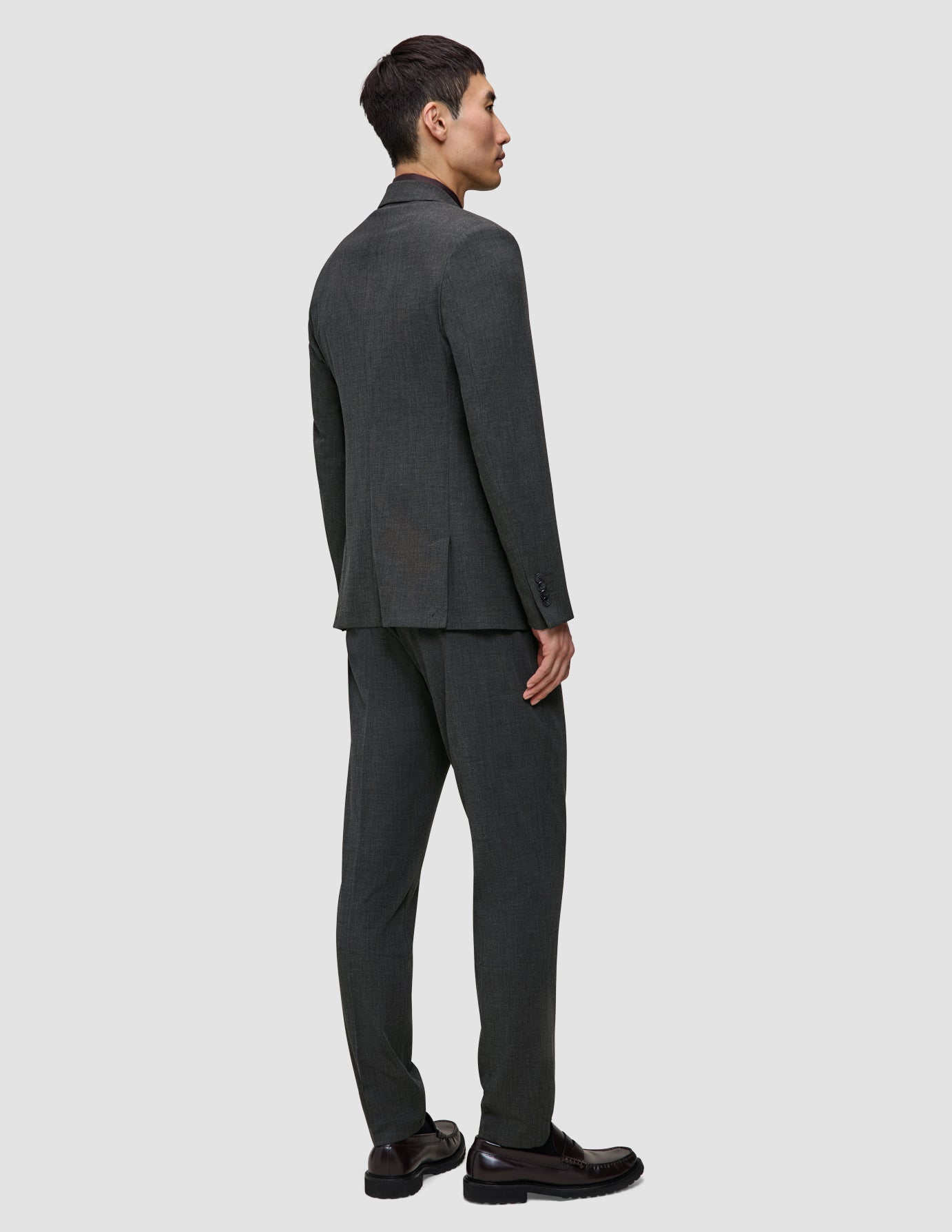 Ein Mann, von hinten gesehen, der einen Motion Blazer Slim in der Farbe Pepper Grey und eine dazu passende Hose im schlichten, skandinavischen Design trägt.