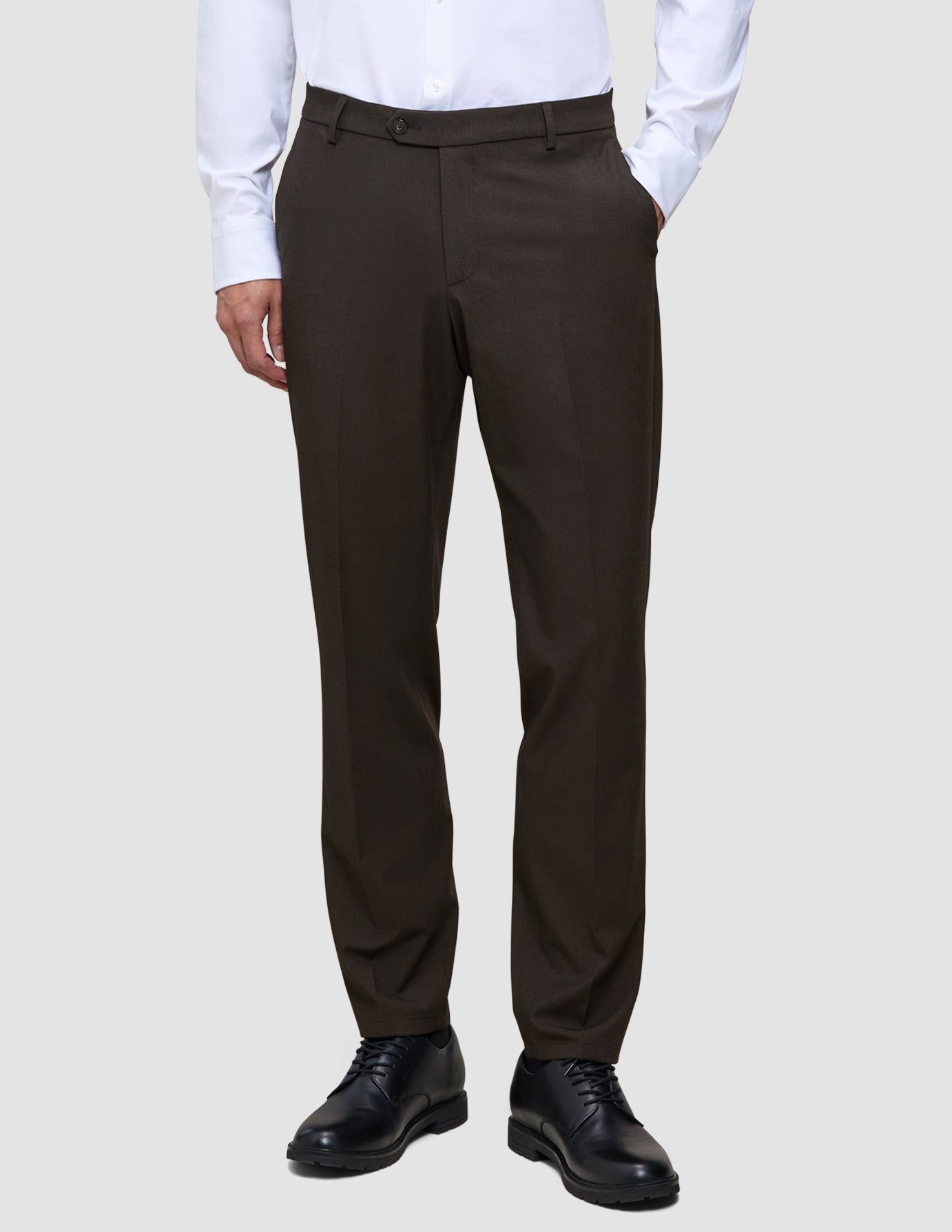Eine Person, die ein weißes Hemd, eine Motion Suit-Hose in der Passform Regular in der Farbe Cognac und schwarze Anzugschuhe trägt, um einen eleganten Look zu erzielen.