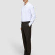 Ein Mann, im Profil zu sehen, der ein weißes, langärmeliges Hemd mit Knöpfen, eine Motion Suit-Hose in der Passform Regular in der Farbe Cognac sowie schwarze Anzugschuhe trägt und damit einen eleganten Look präsentiert.