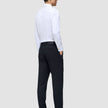 Ein Mann, von hinten gesehen, der ein weißes Hemd, Slipper und eine Motion Suit-Hose in der Passform Regular in Mitternachtsblau trägt.