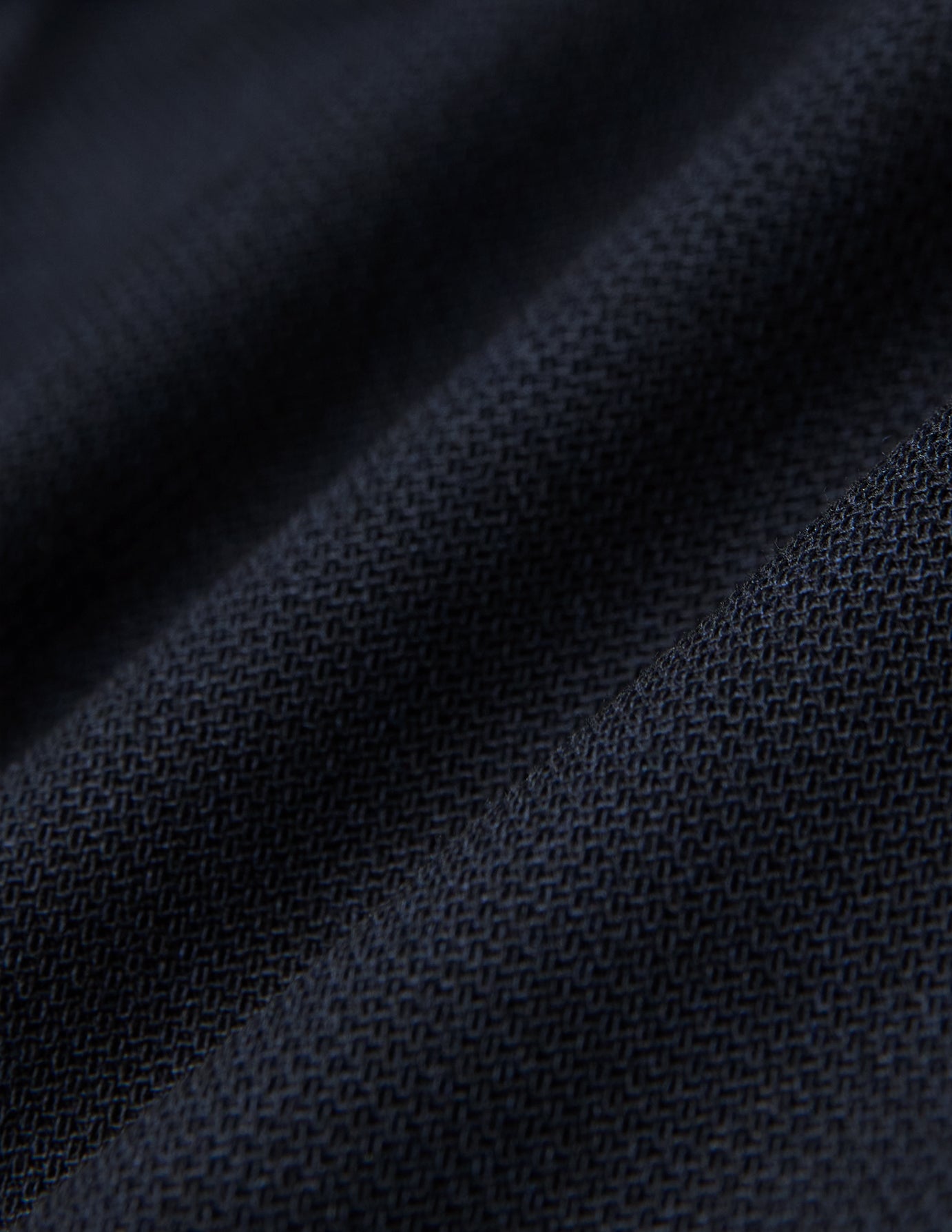 Nahaufnahme einer gefalteten Motion Suit-Hose in der Passform Regular in Mitternachtsblau mit einer sichtbaren, gewebten 360°-Stretch-Struktur.