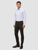 Ein Mann in einem weißen Hemd und einer schmal geschnittenen Motion Suit-Hose in der Farbe Slim Cognac, kombiniert mit schwarzen Lederstiefeln für einen eleganten Look.