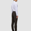 Ein Mann steht im Profil da und trägt ein weißes Hemd sowie eine Motion Suit Pants Slim Cognac – ein eleganter Look.
