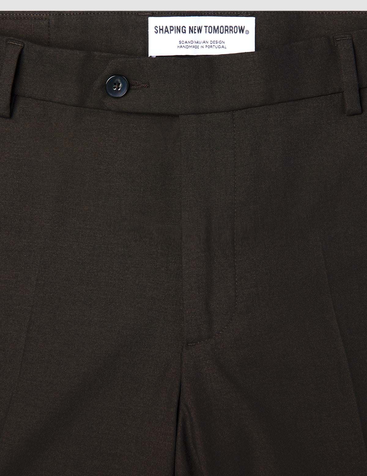 Nahaufnahme der braunen Motion Suit-Hose Slim Cognac mit 360°-Stretch, Ein-Knopf-Verschluss und Markenlabel am Bund.