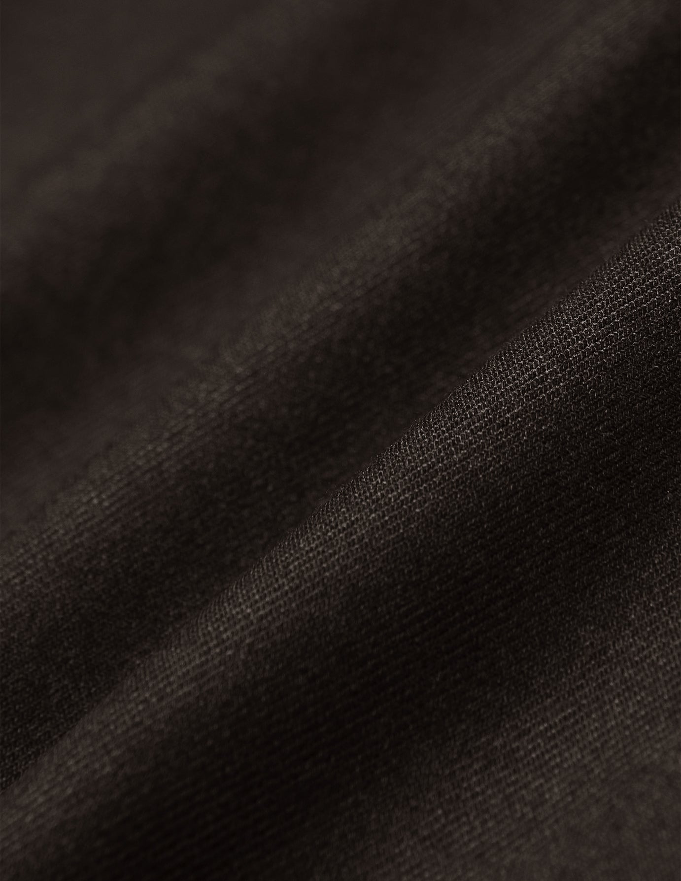Nahaufnahme der dunkelbraunen Motion Suit Pants Slim Cognac aus einem 360°-Stretchstoff mit feiner Webstruktur und weichen Falten, die für einen eleganten Look sorgen.