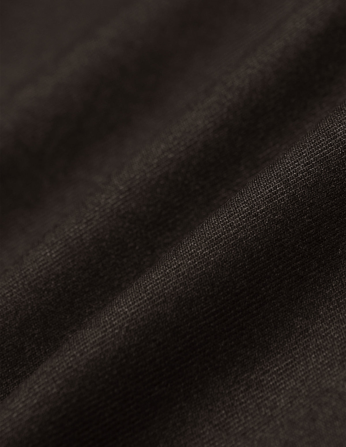 Nahaufnahme der dunkelbraunen Motion Suit Pants Slim Cognac aus einem 360°-Stretchstoff mit feiner Webstruktur und weichen Falten, die für einen eleganten Look sorgen.