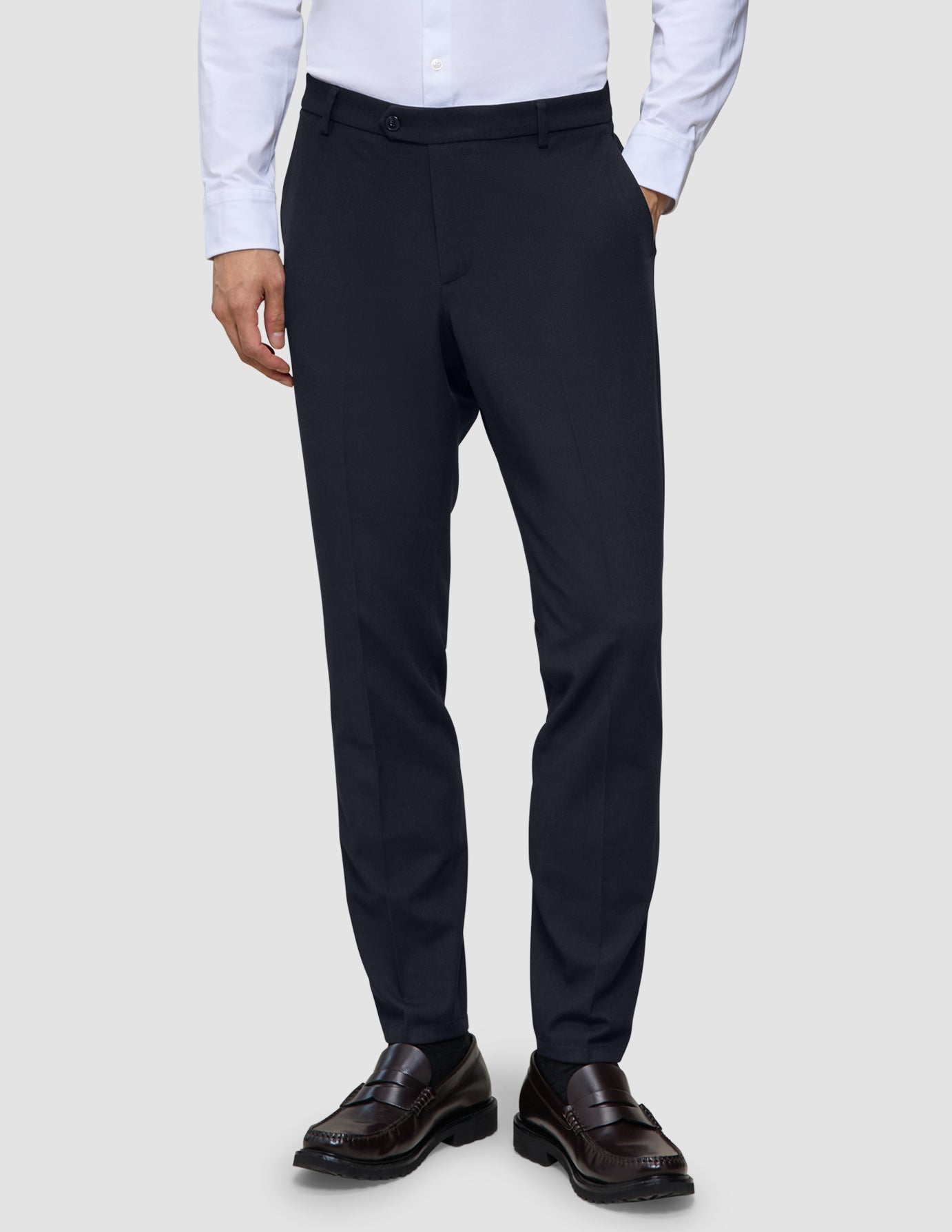 Motion-Anzughose, Slim-Fit, mitternachtsblau, kombiniert mit einem hellen Hemd und dunklen Loafern.