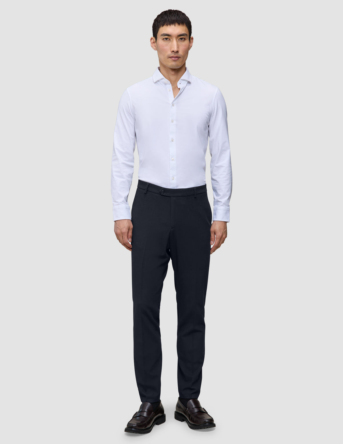 Ein Mann, der ein weißes Hemd und eine dunkelblaue, schmal geschnittene Motion Suit Pants Slim Midnight Blue trägt.