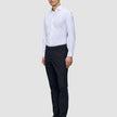 Ein Mann, der ein weißes, langärmeliges Hemd mit Knöpfen und eine Motion Suit Pants Slim in Mitternachtsblau trägt.