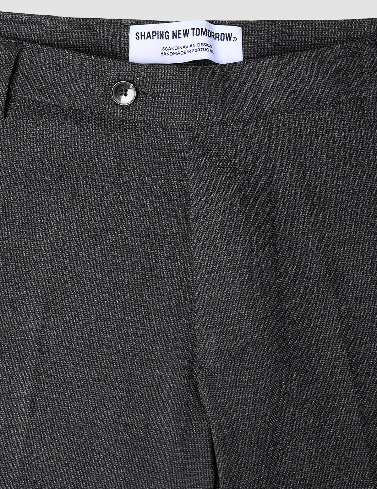 Nahaufnahme der Motion Suit-Hose Slim Pepper Grey in Dunkelgrau, mit schmaler Passform, Knopfverschluss und Markenetikett am Bund.
