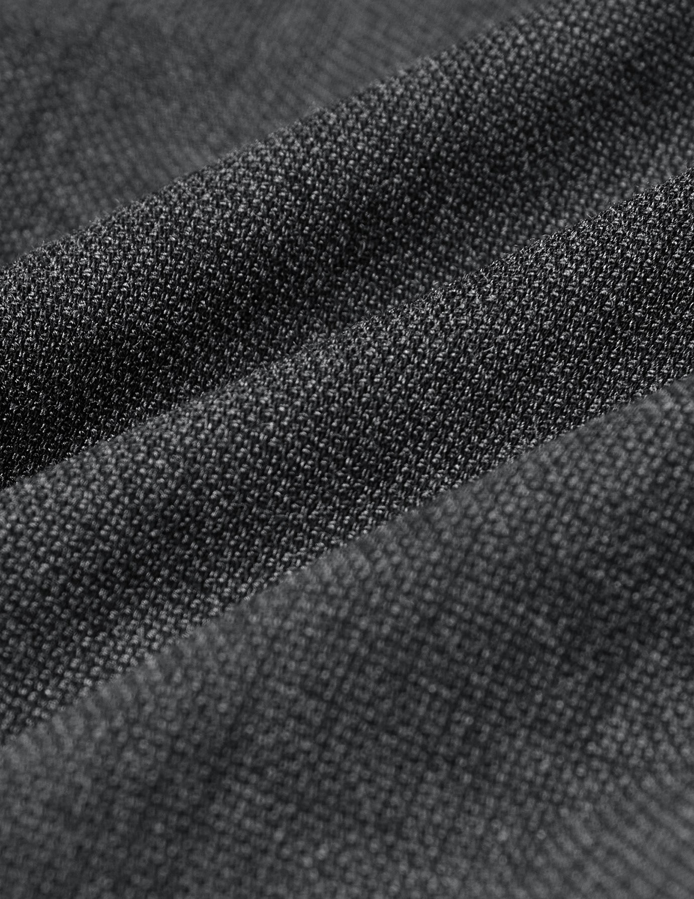Nahaufnahme des grauen, strukturierten, strickartigen Stoffes der Motion Suit Pants Slim Pepper Grey, der sich in sanften Falten legt.
