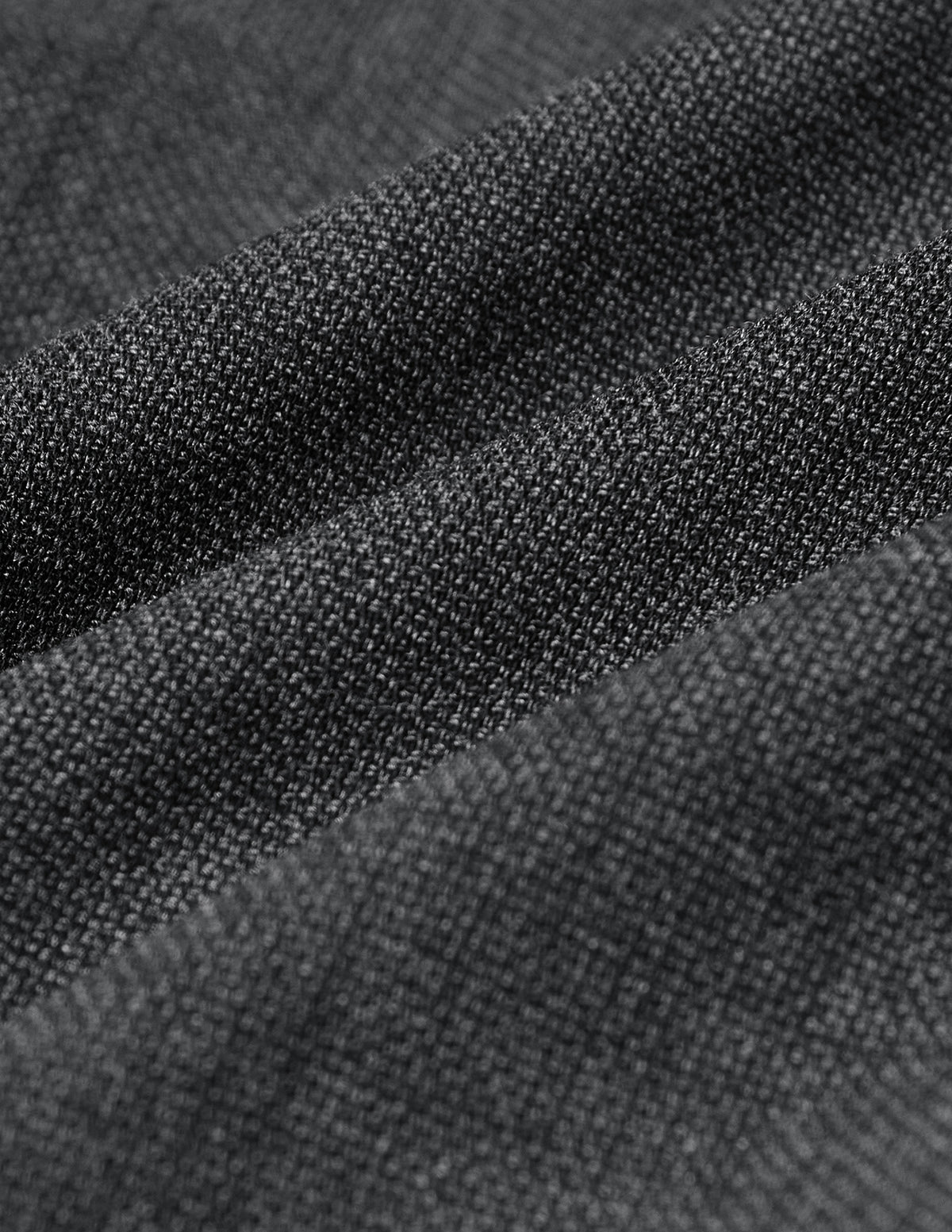 Nahaufnahme des grauen, strukturierten, strickartigen Stoffes der Motion Suit Pants Slim Pepper Grey, der sich in sanften Falten legt.