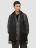 Ein Mann trägt eine dunkelbraune Jacke über einem schwarzen Hemd und einen Scarf Black, einen langen, mit Fransen verzierten Schal aus Kaschmirwolle im minimalistischen skandinavischen Design.