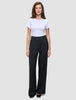 Eine Person, die ein weißes, kurzärmeliges T-Shirt mit Rundhalsausschnitt und die Serene Pants Wide Black trägt – eine Hose mit hoher Taille und weitem Bein im skandinavischen Design.