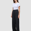 Eine Frau trägt ein weißes T-Shirt und die Serene Pants Wide Black – eine Hose mit weitem Bein und hoher Taille im minimalistischen, skandinavischen Design.