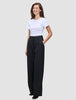 Eine Frau trägt ein weißes T-Shirt, das sie in eine hoch taillierte, weit geschnittene Serene Pants Wide Black gesteckt hat.