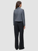 Eine Frau, von hinten gesehen, die einen grauen Blazer und eine schwarze Serene Pants Wide Black mit weitem Bein trägt.
