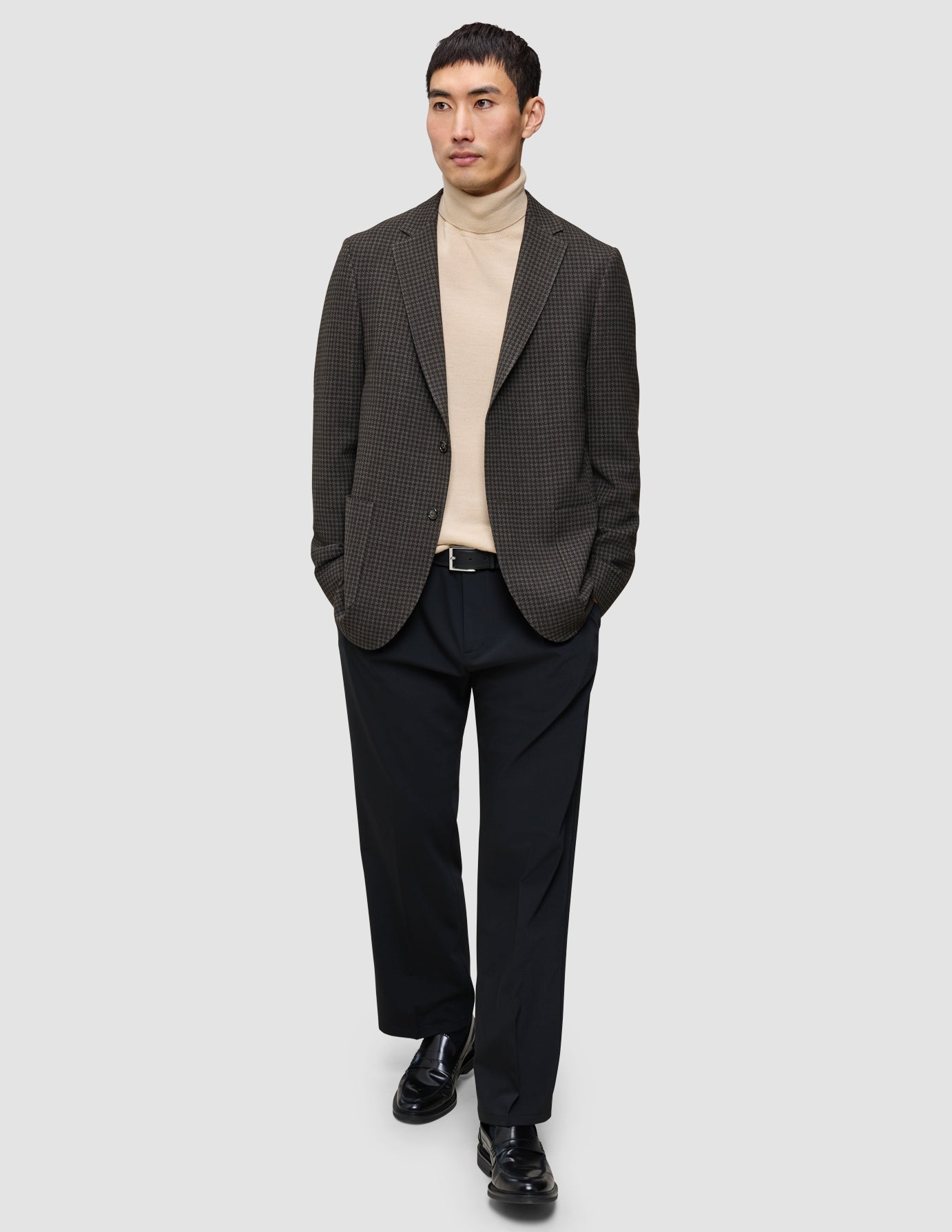 Der Look aus Strickpullover und Blazer: ein beiger Merino-Strickpullover unter einem Timeless Wool Blazer, dazu eine schwarze Hose und schwarze Loafer.