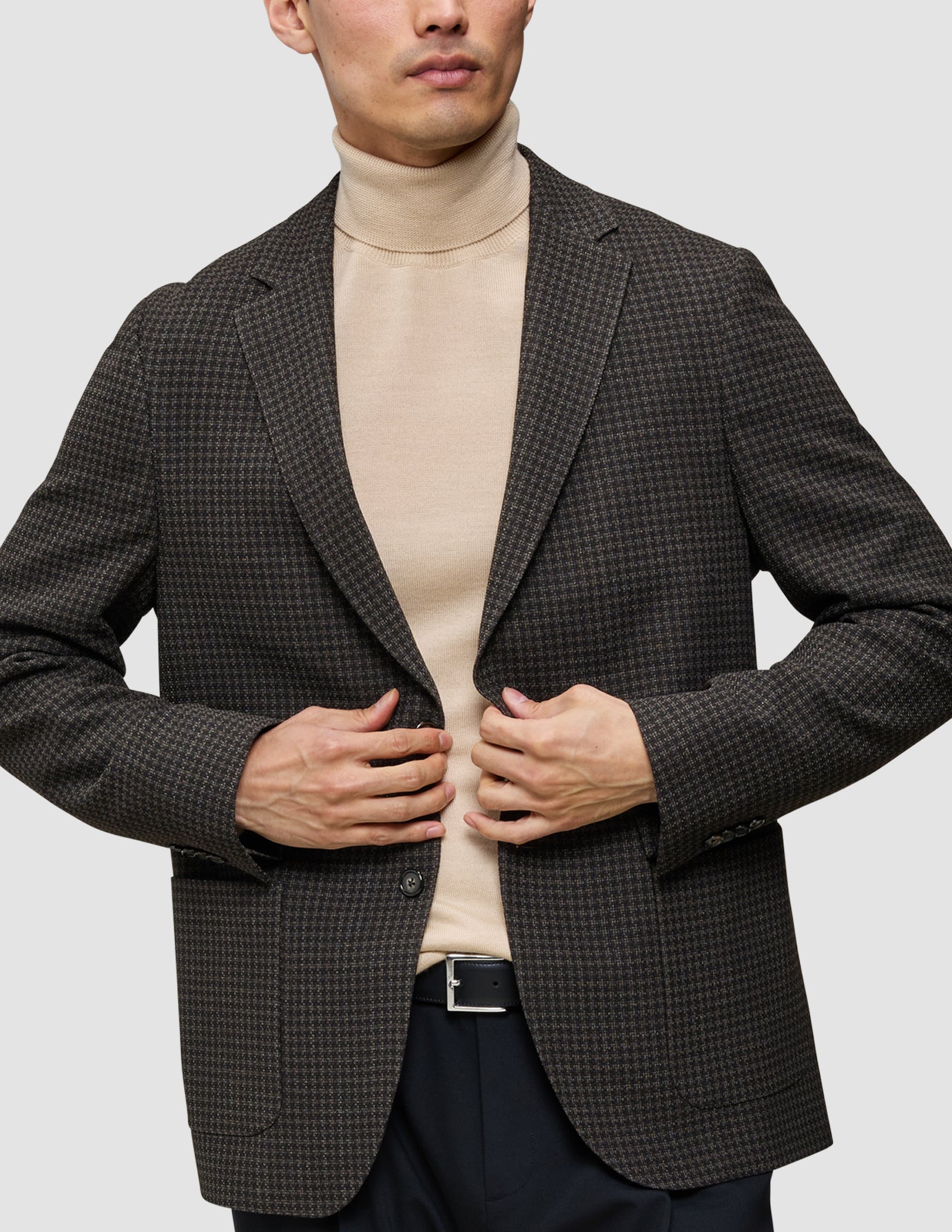 Ein Mann, der einen Pullover aus Merinowolle unter einem zeitlosen Wollblazer trägt – der Strick-und-Blazer-Look.