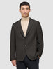 Ein Mann, der einen dunkelbraunen, karierten Timeless Wool Blazer Slim über einem beigen Rollkragenpullover trägt.